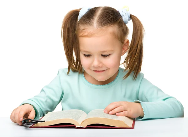 Küçük kız gözlüklü ise bir kitap okur. — Stok fotoğraf