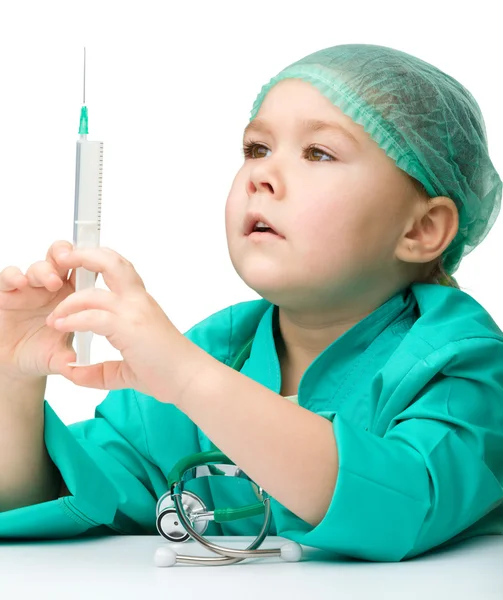 Söt liten flicka spelar läkare med spruta — Stockfoto