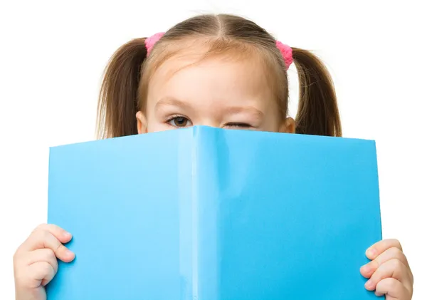 Schattig klein meisje is verstopt achter een boek — Stockfoto