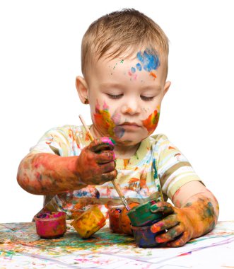 Little boy is playing with paints clipart