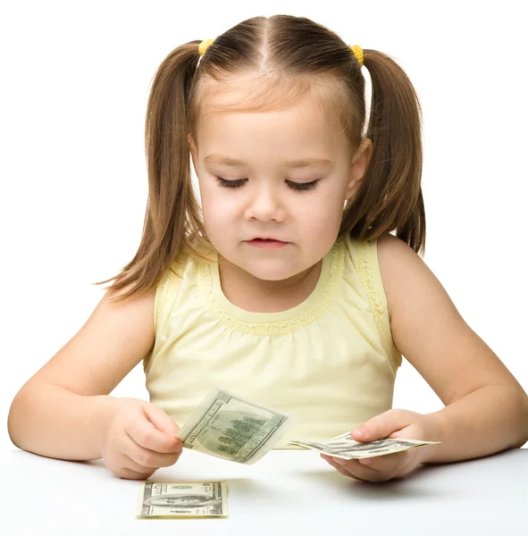 Nettes fröhliches kleines Mädchen zählt Dollars — Stockfoto