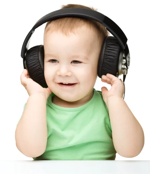 Schattige kleine jongen genieten van muziek met behulp van de hoofdtelefoon — Stockfoto