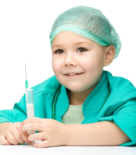 Söt liten flicka spelar läkare med spruta — Stockfoto