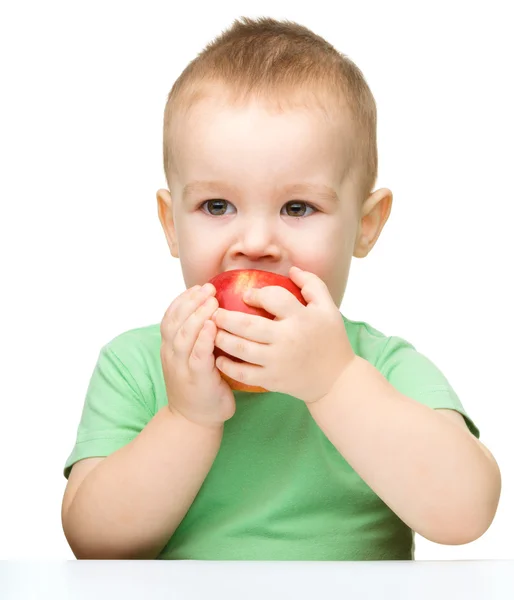 Cute little child is biting red apple — Stock Photo, Image
