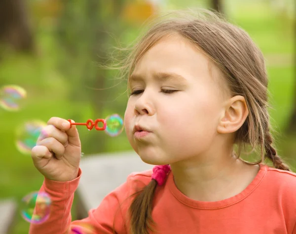 Cute little girl is blowing soap bubbles — Stock Photo, Image