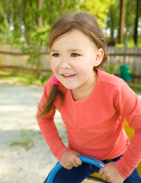 Happy little girl is swinging on see-saw — Stock Photo, Image