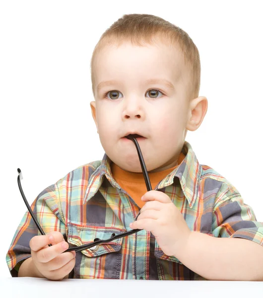 Cute little child is biting glasses — Stock Photo, Image