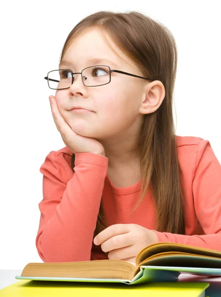 Милая маленькая девочка мечтает во время чтения книги — стоковое фото