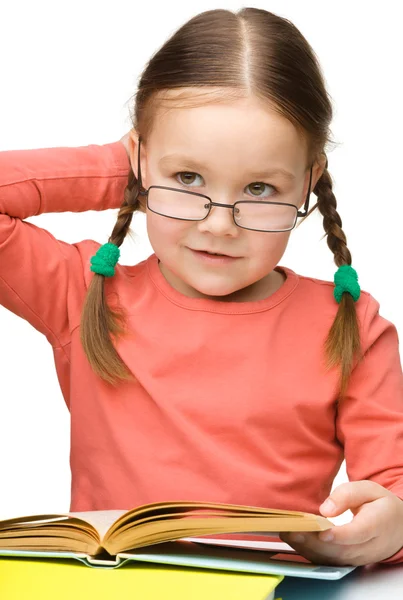 Linda niña leyendo libro con gafas — Foto de Stock