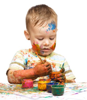 Little boy is playing with paints clipart