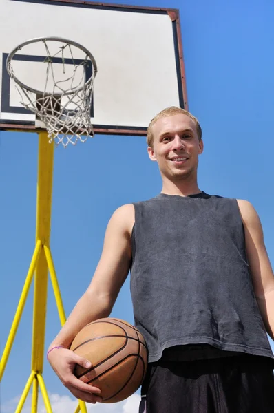 Basketball player posing in front of backboard — Stock Photo, Image