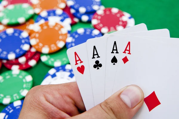 Poker, cuatro ases en la mano sobre una mesa de casino llena de ch —  Fotos de Stock