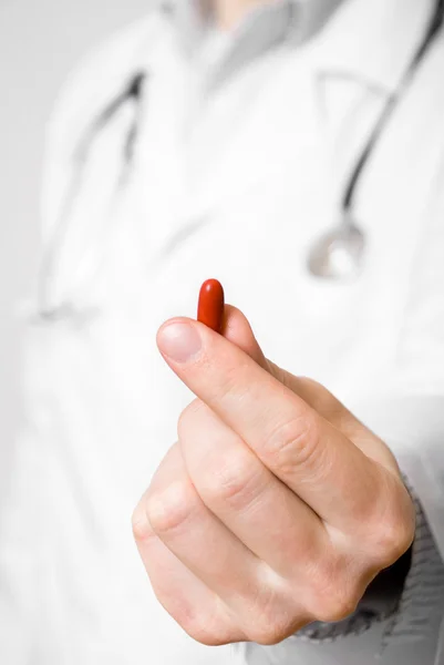Läkare isolerad på grå bakgrund erbjuder piller — Stockfoto