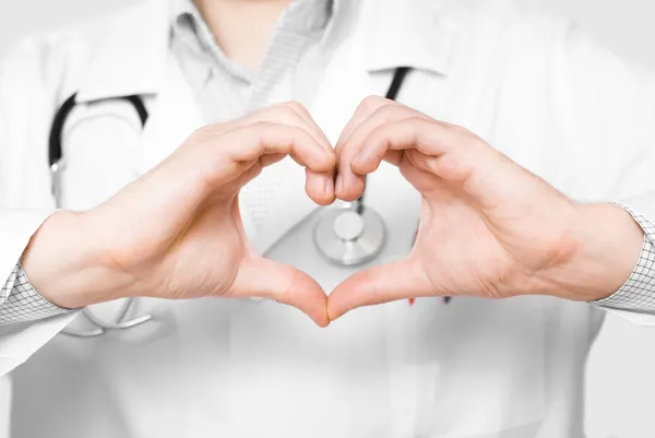 Médico jovem com dedos em forma de coração no fundo branco — Fotografia de Stock