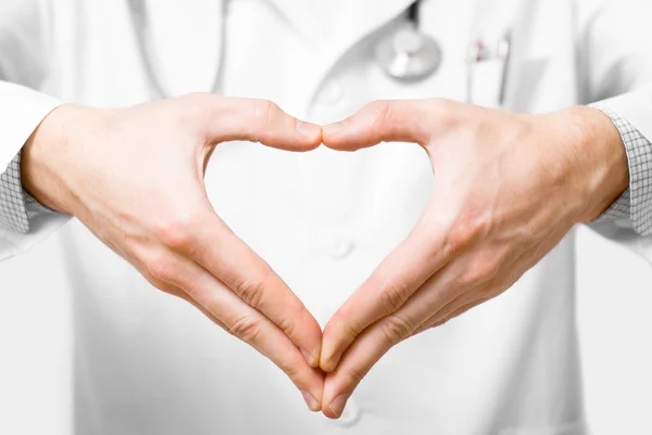 Молодой доктор с руками в форме сердца на белом фоне — стоковое фото
