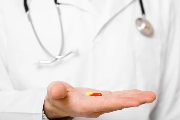 Доктор изолирован на сером фоне предлагая таблетки на ладони — стоковое фото