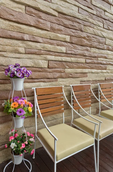 Kleurrijke bloemen stoel en stenen muur — Stockfoto