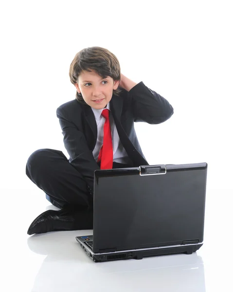 Junge im Businessanzug sitzt vor dem Computer Stockbild