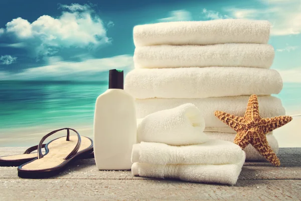 Lotion, towels and sandals with ocean scene Stock Photo