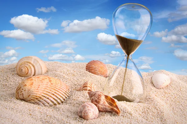 Пісочний годинник в піску з блакитним небом — стокове фото