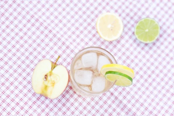 Água com limão e limão, maçã em um copo com gelo — Fotografia de Stock