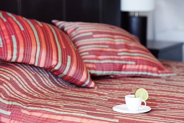 Кровать с двумя подушками, чашка чая на одеяле — стоковое фото