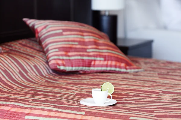 Κρεβάτι με δύο μαξιλάρια, ένα φλιτζάνι του τσαγιού στην κουβέρτα — Φωτογραφία Αρχείου