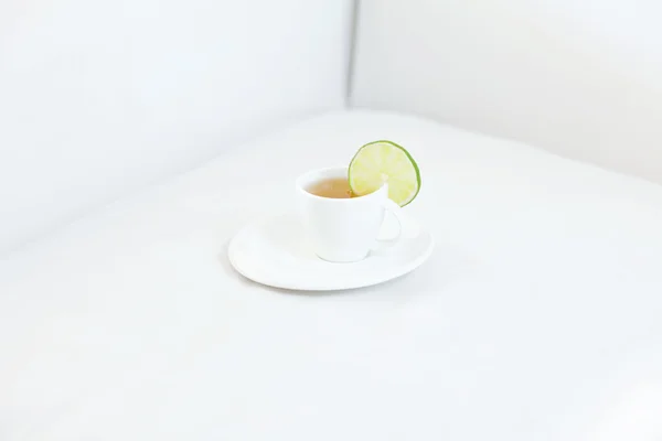 Cup of tea with lime on sofa — Stock Photo, Image
