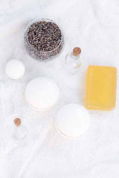 Cosmetische containers, flessen, zeep en lavendel op een witte handdoek — Stockfoto
