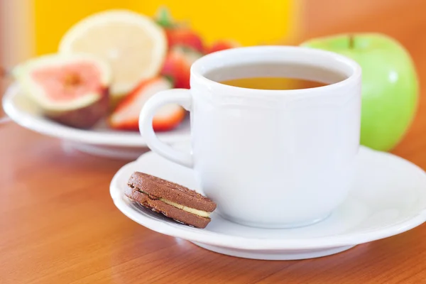 Taza de té, galletas, manzana, limón, higo y fresas en un plato —  Fotos de Stock