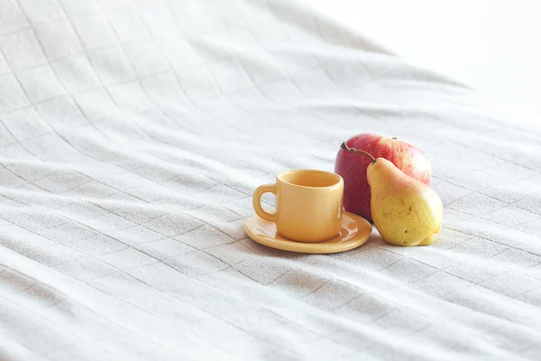 Kopp te, äpple och päron på sängen — Stockfoto