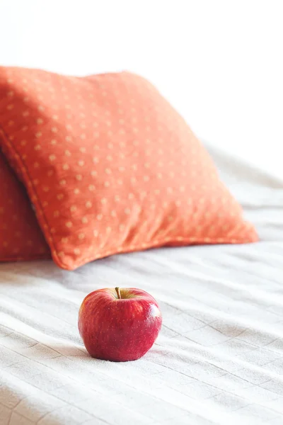 Яблоко на кровати с двумя подушками — стоковое фото
