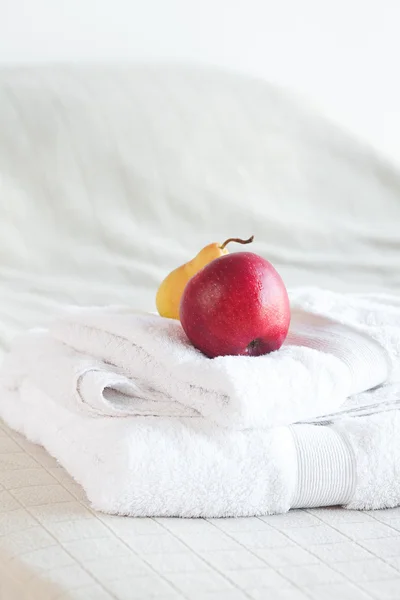 Яблоко и груша на полотенцах на кровати — стоковое фото