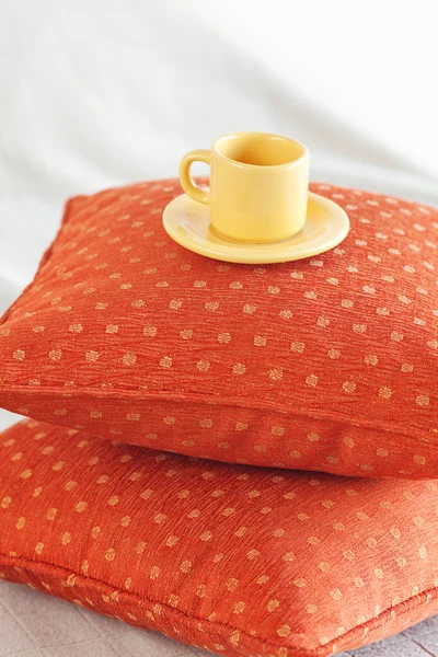 Чашка, лежащая на подушках на кровати — стоковое фото