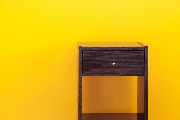 Mesa de cabeceira contra uma parede amarela no apartamento — Fotografia de Stock