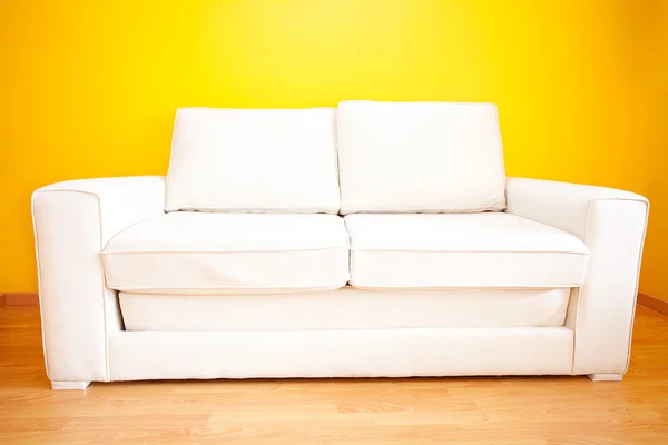 Biała kanapa żółtą ścianę w mieszkaniu — Zdjęcie stockowe