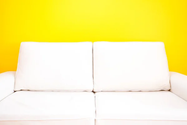 Λευκό καναπέ ενάντια σε έναν κίτρινο τοίχο στο διαμέρισμα — Φωτογραφία Αρχείου