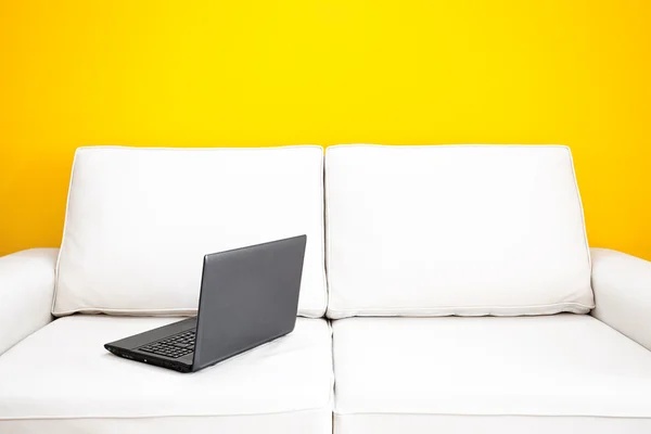 白色沙发和一堵黄墙在公寓里的便携式计算机 — 图库照片
