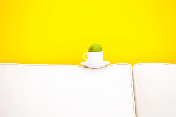 Vit soffa och kopp med tangerine mot en gul vägg det en — Stockfoto