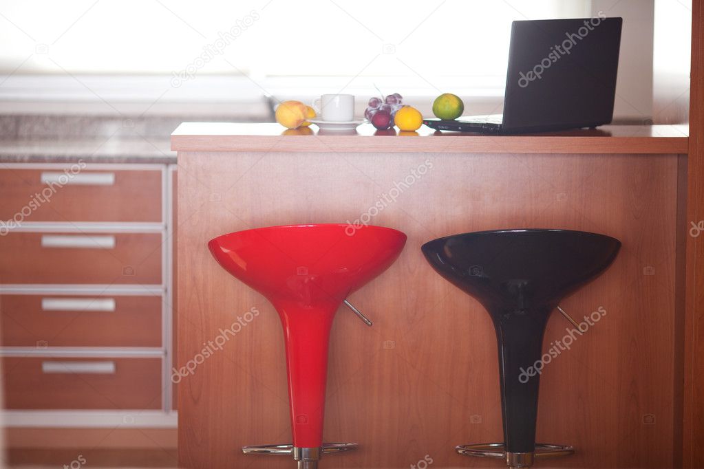 Kitchen interior with bar chairs,laptop and fruits in the apartm