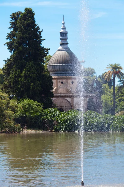 Palm trees, trees and a fountain against the blue sky — Stock Photo, Image