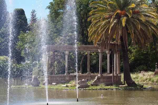 Palmy, drzewa i fontanna przed błękitne niebo — Zdjęcie stockowe