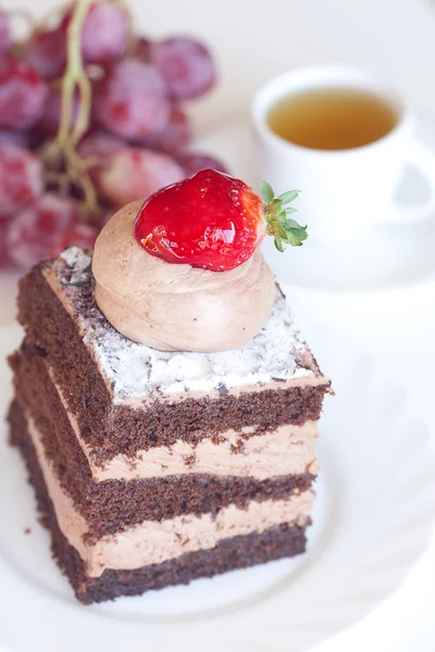 Vacker tårta med jordgubbar, vindruvor och te på en vit backgro — Stockfoto