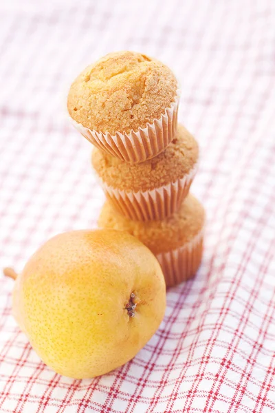 Three muffins and pear on plaid fabric — Stock Photo, Image