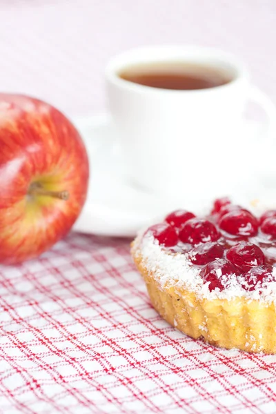 Vacker tårta med bär, äpple och te på rutigt tyg — Stockfoto