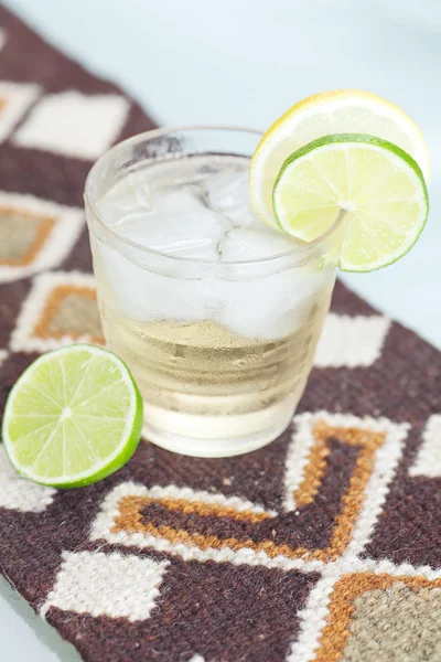 Water met citroen en limoen in een glas met ijs op etnische mat — Stockfoto