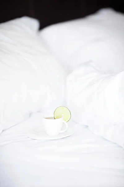 Кровать с подушкой и чашкой чая — стоковое фото
