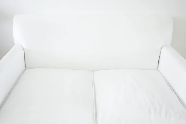 Sofá blanco sobre un fondo de pared blanco —  Fotos de Stock