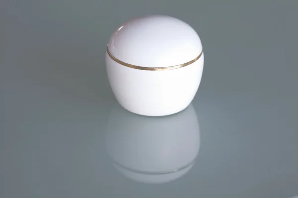 Um recipiente cosmético na superfície de vidro — Fotografia de Stock