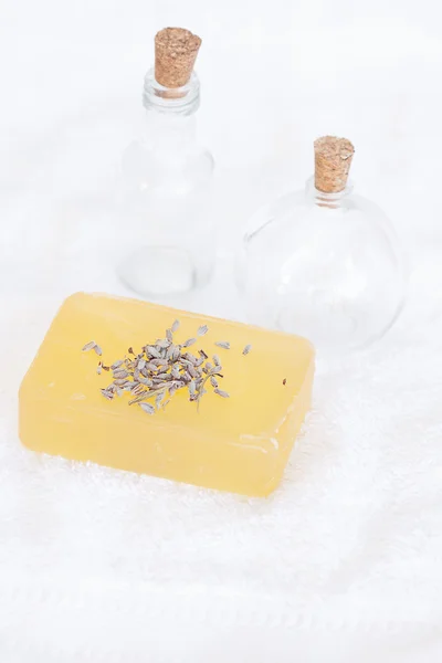 Flessen, zeep en lavendel op een witte handdoek — Stockfoto